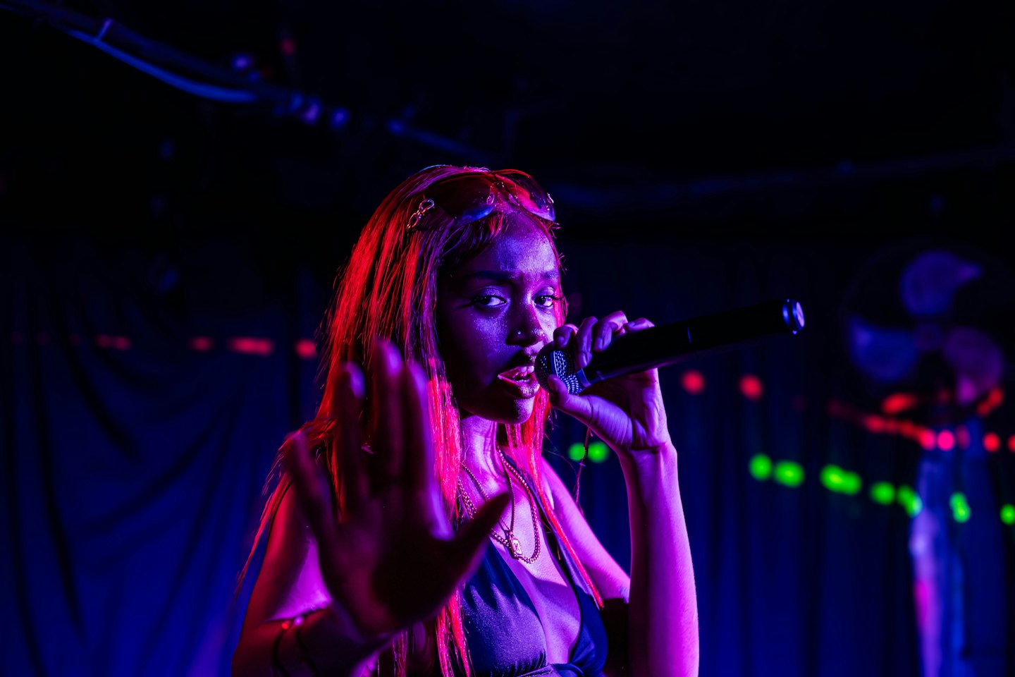 A woman sings into a microphone while performing on stage.
