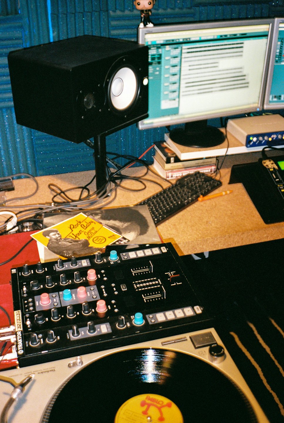 Music production desk with turntable, DJ mixer, and monitors.