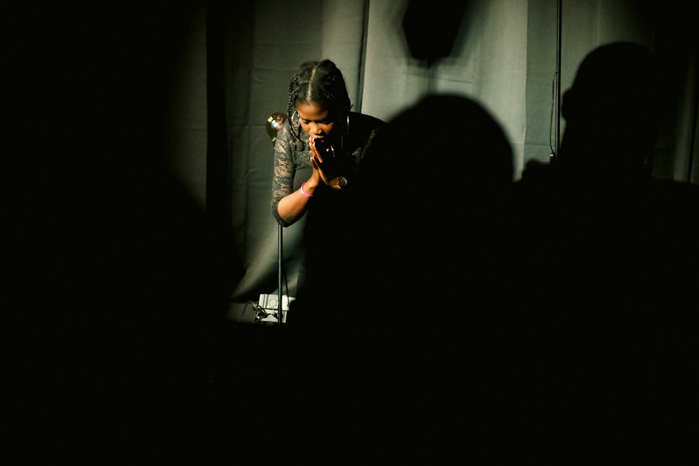 A Black woman sings into a microphone on a stage.